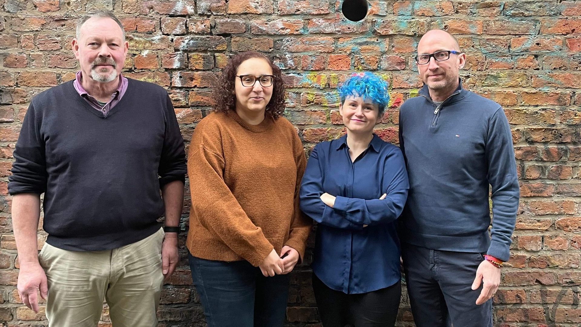 Four of Gaddum's traumatic bereavement therapy team against an industrial brick wall in Manchester