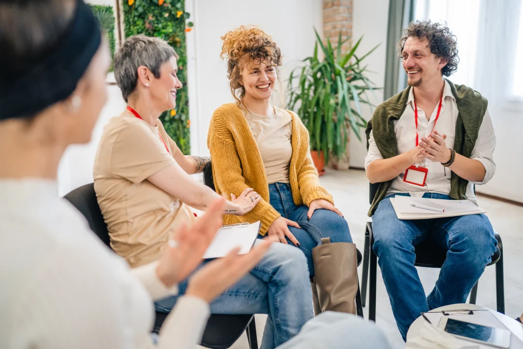 A,Group,Of,People,Sitting,In,A,Circle,With,Two