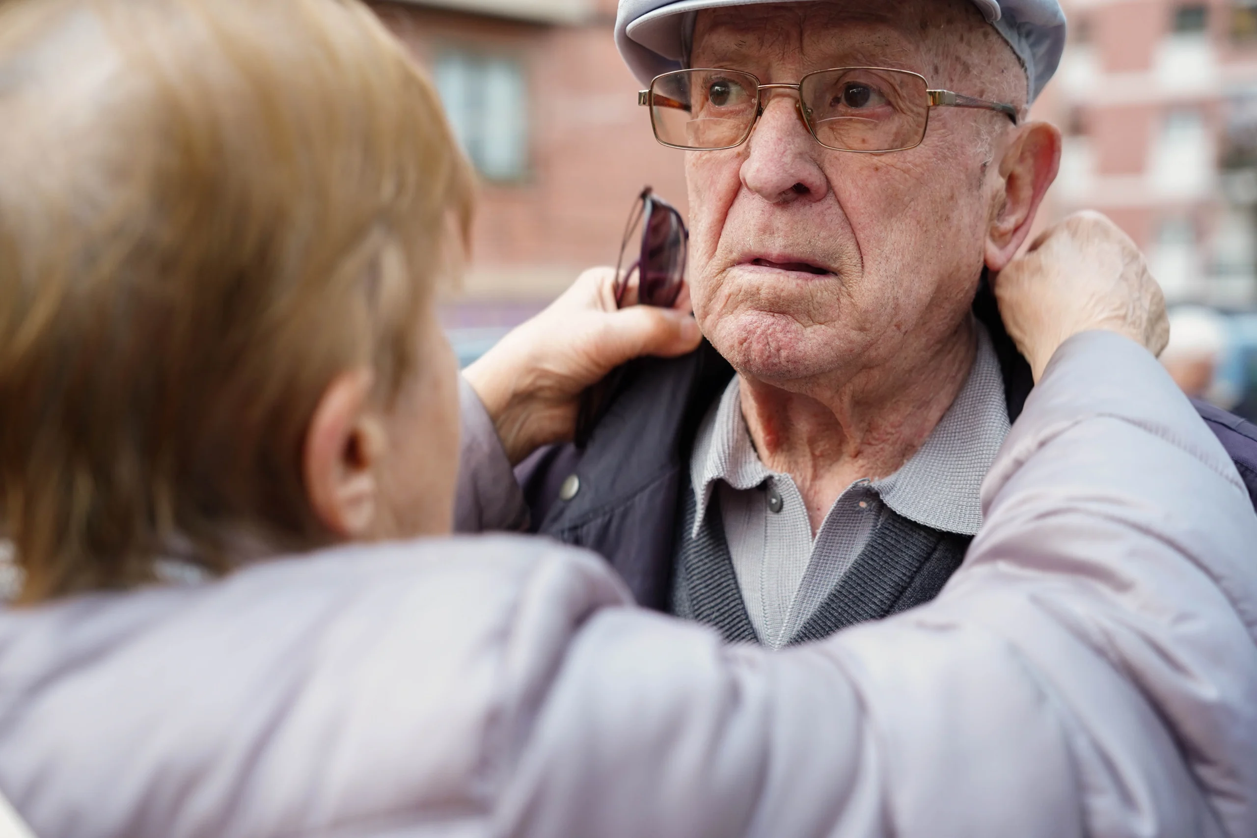 An,Old,Woman,Helps,His,Husband,Get,Dressed,Outside.,Dependency